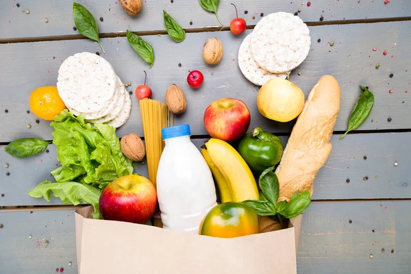 Bakkal alışveriş kavramı. Kağıt torba ahşap arka plan üzerinde farklı yiyecek. Düz yatıyordu.