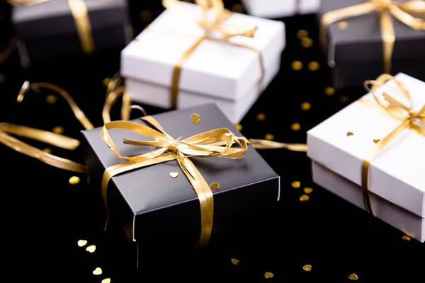 Cajas de regalo en blanco y negro con cinta dorada sobre fondo brillante. De cerca. . — Foto de Stock