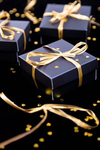 Cajas de regalo negras con cinta dorada sobre fondo brillante. De cerca. . — Foto de Stock