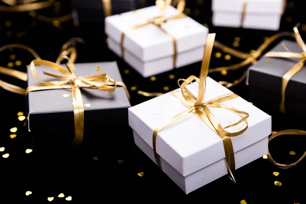 Cajas de regalo en blanco y negro con cinta dorada sobre fondo brillante. De cerca. . — Foto de Stock