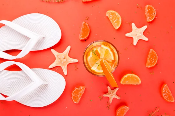 Summer vacation. Orange fruit cocktail, detox water near white flip flops. — Stock Photo, Image