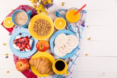 Sağlıklı kahvaltı. Çeşitli ürün yelpazesine sahip küme. Portakal suyu, Granola, kruvasan, kahve ve meyve.