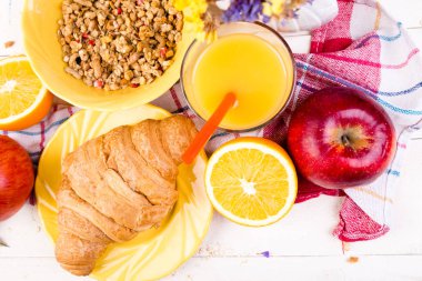 Sağlıklı kahvaltı. Çeşitli ürün yelpazesine sahip küme. Portakal suyu, Granola, kruvasan ve meyve.