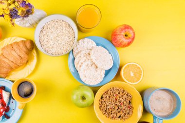 Sağlıklı kahvaltı. Çeşitli ürün yelpazesine sahip küme. Portakal suyu, Granola, kruvasan, kahve ve meyve.