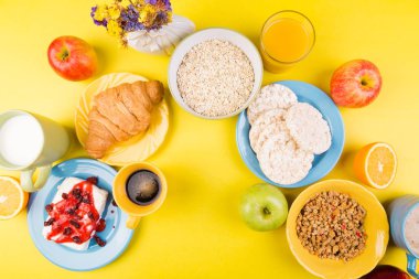 Sağlıklı kahvaltı. Çeşitli ürün yelpazesine sahip küme. Portakal suyu, Granola, kruvasan, kahve ve meyve.