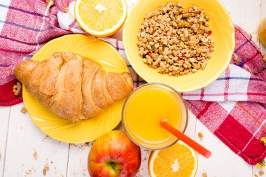 Sağlıklı kahvaltı. Çeşitli ürün yelpazesine sahip küme. Portakal suyu, Granola, kruvasan ve meyve.