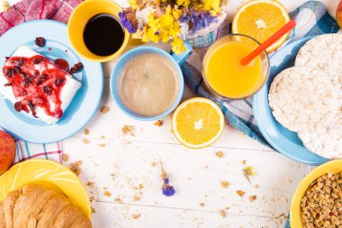 Sağlıklı kahvaltı. Çeşitli ürün yelpazesine sahip küme. Portakal suyu, Granola, kruvasan, kahve ve meyve.