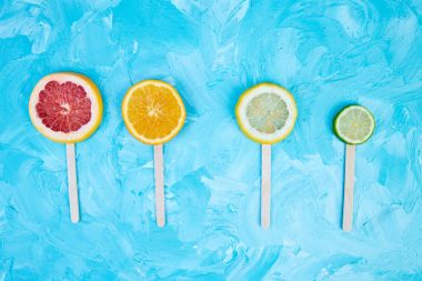 Mavi bir arka plan üzerinde narenciye dilim popsicles. 