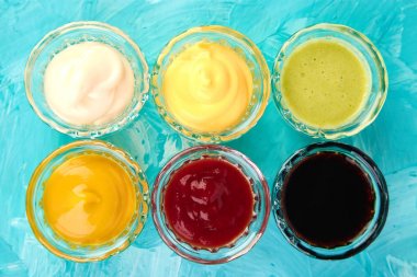 Farklı sos kümesi. Soslar ketçap, hardal, mayonez, wasabi, mavi zemin üzerine küçük kase soya sosu