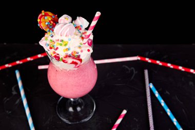 Berry, rasberry, çilek, çikolata şekerleme, lolipop siyah arka plan üzerine pembe aşırı milkshake... Deli freakshake. Uzay kopyalayın. Gıda trend Overshake