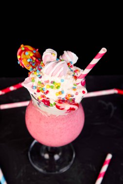 Berry, rasberry, çilek, çikolata şekerleme, lolipop siyah arka plan üzerine pembe aşırı milkshake... Deli freakshake. Uzay kopyalayın. Gıda trend Overshake