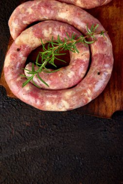 Biberiye, tuz ve peper ahşap kesme tahtası üzerinde ham sarmal domuz sosisi. Üstten Görünüm, metin için yer. Kopya alanı.