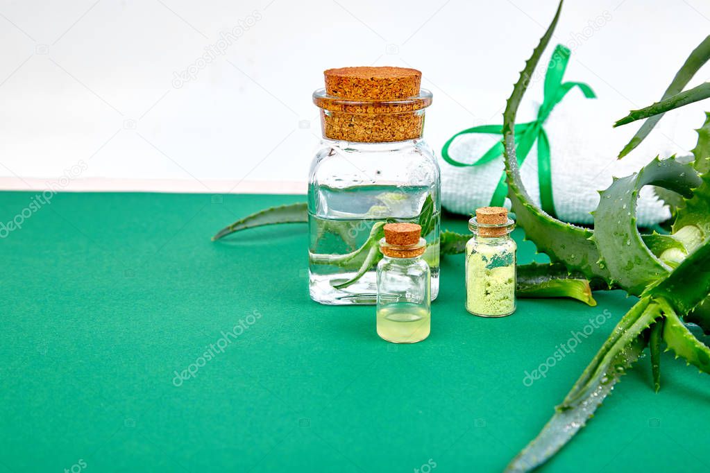 Aloe vera oil in glass bottle and towel for spa on green background. Star cactus, Aloin, Jafferabad, Aloe barbadensis, Barbados herbal medicine for skin treatment and care. Copy space