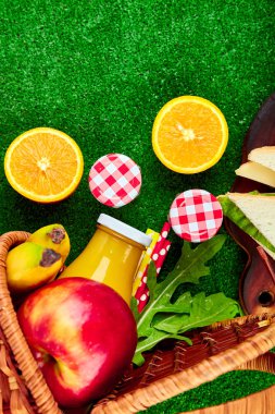 Çimlerde piknik. Kırmızı masa örtüsü, sepet, sağlıklı gıda sandviç ve meyve, portakal suyu kontrol ettim. Üstten görünüm. Yaz Saati dinlenme. Düz yatıyordu.