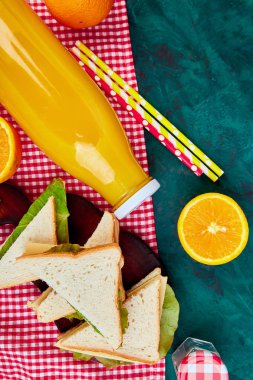 Yeşil tablo pikniğe. Kırmızı masa örtüsü, sepet, sağlıklı gıda sandviç ve meyve, portakal suyu kontrol ettim. Yaz Saati dinlenme. Düz yatıyordu