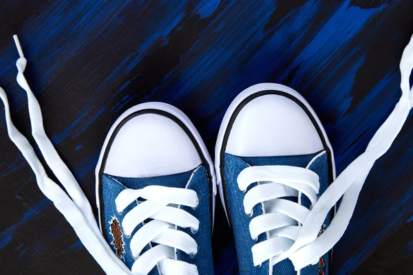 Flat lay of female or male sneakers shoes on a blue background. Copy space. Top view. Spring or summer outfit. Fashion. Woman or man, Girl, Boy