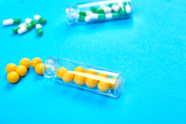 Tıbbi blog için minimalizm tarzı şablonu. Küçük renk hapları ile küçük cam şişe mavi arka plan dışarı dökülen. Farmasötik konsept. İlaç hapları. Düz la