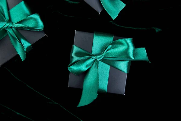 Luxury black gift boxes with green ribbon on shine velvet background. Christmas, birthday party presents. Father Day. Flat lay. Copy space. Top view.