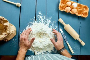 Hamuru un kaplı bir yüzeyde şekillendiren ve elleriyle yoğuran bir adam. Hamur yoğuran fırıncının eli. İşlem hazırlığı ev yapımı hamur işi. Makarna, spagetti, pizza konsepti..