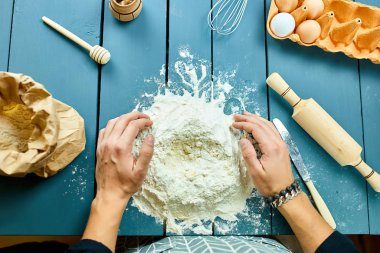 Hamuru un kaplı bir yüzeyde şekillendiren ve elleriyle yoğuran bir adam. Hamur yoğuran fırıncının eli. İşlem hazırlığı ev yapımı hamur işi. Makarna, spagetti, pizza konsepti..