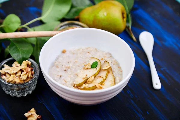 Una ciotola di porridge con fette di pere e noci . — Foto Stock