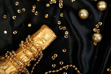 İçinde konfeti yıldızları ve şenlikli siyah arka planda parti flamaları olan altın şampanya şişesi. Noel, doğum günü ya da düğün konsepti. Düz yatıyordu.