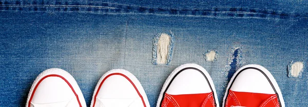 Banner con zapatillas blancas y rojas en un fondo de mezclilla rasgado . — Foto de Stock