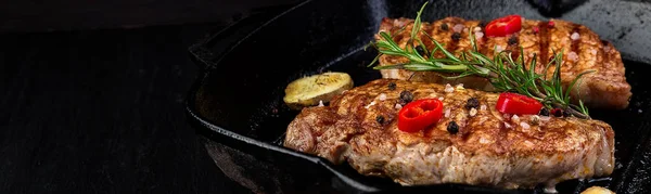 Banner s grilovaným vepřovým steakem v grilované pánvi s rozmarýnem, paprikou a zázvorem na dřevěné desce. — Stock fotografie
