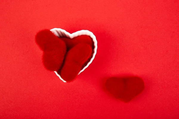 Kırmızı Arka Planda Kırmızı Peluş Kalpleri Olan Beyaz Seramik Kalpler — Stok fotoğraf