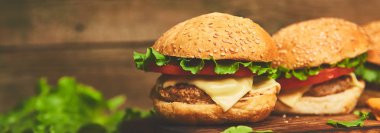 Ahşap masada, siyah arka planda izole edilmiş sığır etli burger pankartı..