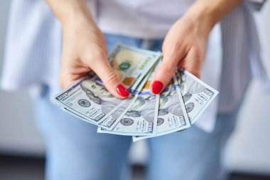 Kadın elinde dolarları tutuyor. Mutluluk kavramı, başarı.