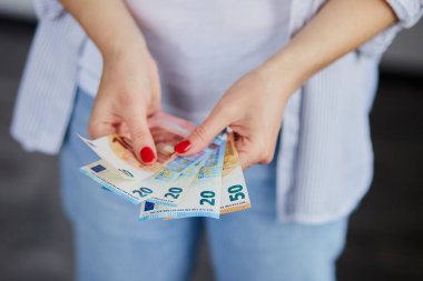 Avro parasını elinde tutan bir kadın var. Coronavirüs 'ten etkilenen ekonomi ve finans piyasaları. Kaydedilmiş para.