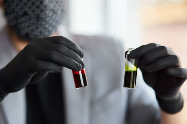Elinde kan ve panzehirle test tüpleri tutan genç bir adam. Coronavirus kan testi tüpü. Bilim adamının elinde pozitif kan örneği var. Kapalı