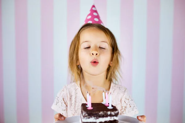 Little Girl Pink Cap Blowing Out Candles Birthday Chocolate Cake Stock Image