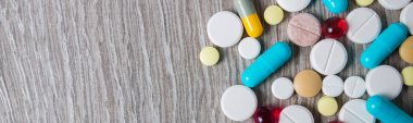 Gri ahşap arka planda bir sürü renkli ilaç ve hapın afişi. Uzayı kopyala Üst manzara, çerçeve. Ağrı kesiciler, haplar, genel ilaçlar, ilaçlar..