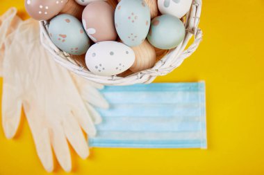 Coronavirus karantinasında paskalya kompozisyonu. Paskalya sembolü yumurtalar koruyucu tıbbi maske ve eldivenlerin yanında. Coronavirüs salgınından dolayı Paskalya tatili konsepti.