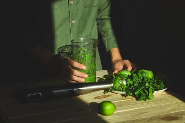 Adam sağlıklı detoks smoothie tutuyor, blender ile pişiriyor.