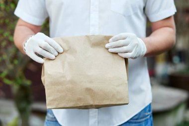 Kurye, tıbbi lateks eldivenli kurye Coronavirus salgını sırasında, COVID-19 'da kahverengi kese kağıtlarıyla çevrimiçi alışveriş yapıyor. Evde kal, güvenli konsept..