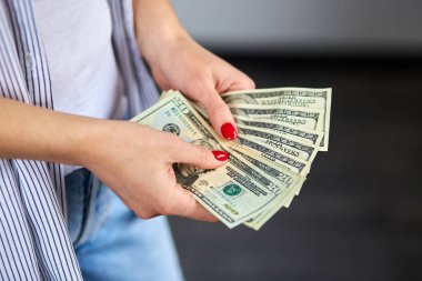 Kadın elinde dolarları tutuyor. Mutluluk kavramı, başarı.