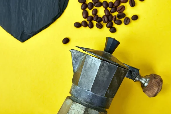 Flat lay of Coffee maker and beans on yellow background. Coffee love concept. Moka coffee pot. Espresso maker. Process of making natural coffee from beans. Top view. Copy space.