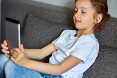 Evde konuşulan videodaki küçük kız tablet toplantısıyla çevrimiçi çağrı arkadaşı Coronavirus sırasındaki karantina izolasyonu. Akıllı telefonlu bir kız selfie çekiyor ya da uzaktan iletişim kuruyor. Evde kal..