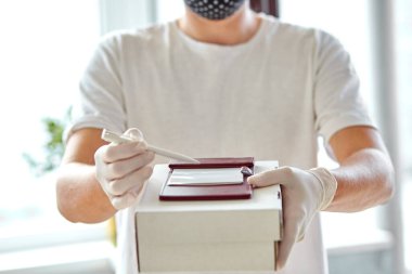 Teslimat servisi karantina altında. Kurye, beyaz eldivenli teslimatçı Coronavirus salgını sırasında güvenli bir şekilde internetten alışveriş yapıyor. Evde kal, güvenli konsept, ulaşılamaz teslimat..
