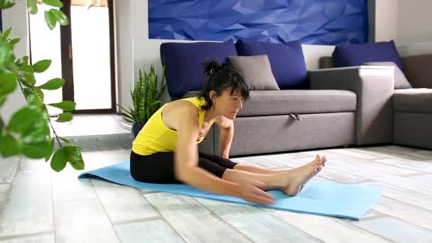 Seniorin trainiert zu Hause, macht Yoga oder Pilates, posiert für die flexible Wirbelsäule. — Stockvideo