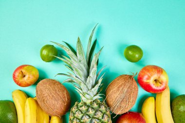 Mavi arka planda egzotik meyveler var. Mango, ananas, muz, avokado, hindistan cevizi, limon. Üst Manzara. Tropikal meyvelerden, fotokopi alanından ve yaz konseptinden oluşan yaratıcı düzen