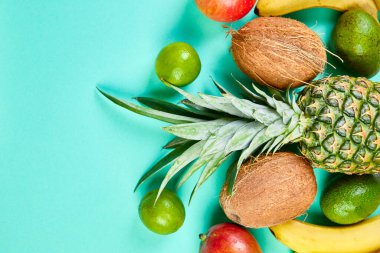 Mavi arka planda egzotik meyveler var. Mango, ananas, muz, avokado, hindistan cevizi, limon. Üst Manzara. Tropikal meyvelerden, fotokopi alanından ve yaz konseptinden oluşan yaratıcı düzen