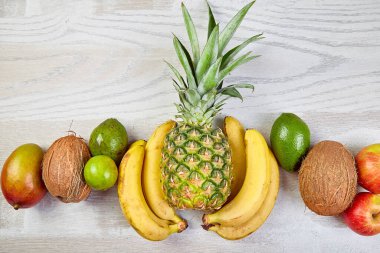 Beyaz arka planda egzotik meyveler var. Mango, ananas, muz, avokado, hindistan cevizi, limon. Üst Manzara. Tropikal meyvelerden, fotokopi alanından ve yaz konseptinden oluşan yaratıcı düzen.