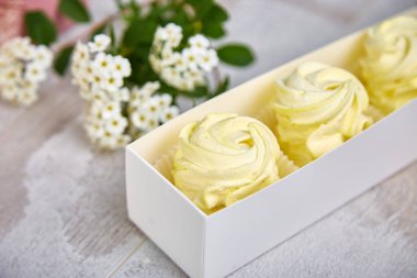 Ev yapımı limon sarısı marşmelovlu hediye kutusu. Çiçek şeklinde elma zephyr. Gül şeklinde. Beyaz ahşap masada lezzetli meyveli tatlı..