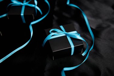 Parlak siyah arka planda mavi kurdeleli lüks siyah hediye kutuları. Noel, doğum günü hediyeleri. Babalar Günü. Düz yatıyordu. Uzayı kopyala Üst görünüm.