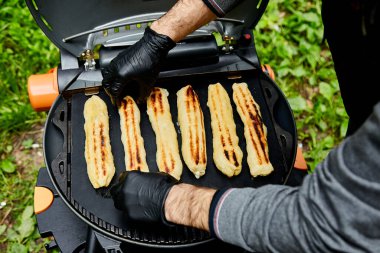 Dışarıdaki ızgarada peynirli börek. Adam pişiriyor, pişiriyor, mangır pişiriyor..