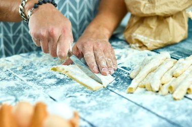 Evde ev yapımı makarna yapma işlemi. Aşçı bıçak ile taze hamur ile kesiyor İtalyan geleneksel makarnası için ince kurdele. İtalyan mutfağı tarifi. Ev yemekleri. Koca mutfakta yemek pişiriyor..